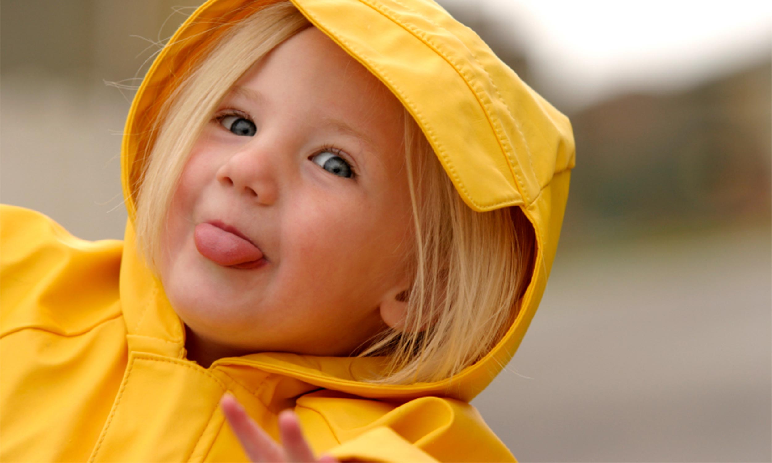 Ein fröhliches Kind, das eine gelbe Regenjacke trägt – Kindergarten in Düsseldorf